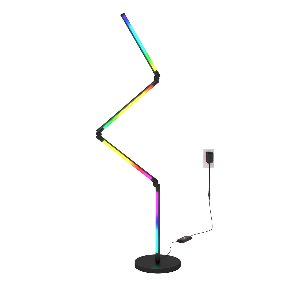 A zigzag-shaped floor lamp with segments glowing in rainbow colors, standing on a black circular base. The lamp is plugged into a wall socket with a visible black cable and adapter.