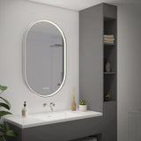 A modern bathroom with a large oval backlit mirror above a white sink, a gray vanity, shelves with towels and toiletries, and a small potted plant on the counter.