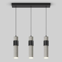 The Artika Barden 3-light LED pendant features cylindrical gray concrete bodies with black bands, suspended in a row from a rectangular black ceiling mount by thin black cords, set against a plain light gray background.