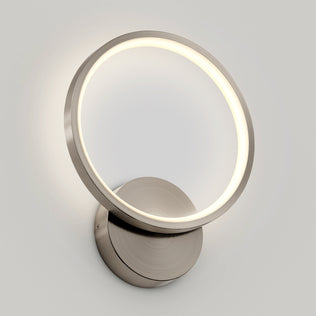 The Artika Solis modern LED indoor-outdoor wall light 5 CCT features a sleek circular ring and metallic base, casting a soft, warm glow—ideal accent lighting for contemporary spaces.