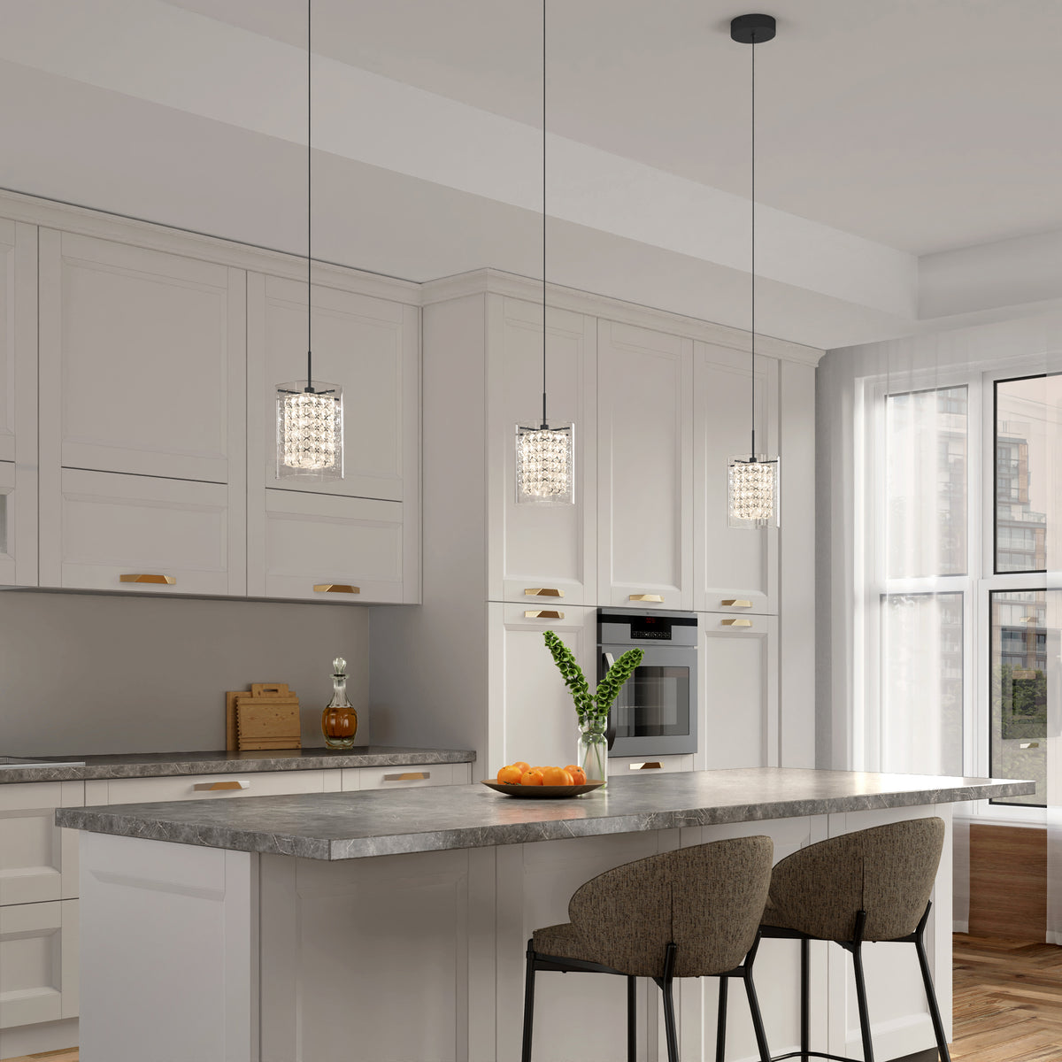 Modern kitchen with white cabinets, gray marble countertop island, two upholstered barstools, three pendant lights, a vase with green leaves, and a bowl of oranges. Sunlight streams in through large windows.