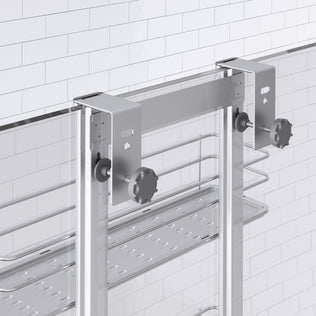 Close-up of the Artika Camden Shower Caddy, a modern glass shower door organizer with metal brackets and knobs, plus a metal shelf and towel rail mounted below the brackets on a tiled bathroom wall.