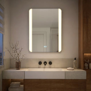 Modern bathroom with Artika Onyx LED Mirror with Defogger, sink, chrome faucets, soap dispenser, and a decorative branch in a vase.