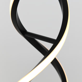 A close-up of the Artika Swirl LED table lamp, featuring a sleek, twisted black frame with a subtle chrome finish and a continuous warm white light strip, set against a plain light gray background.