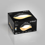 Black and gold Artika Adara ceiling light packaging box displayed on a gray background, showing the product image and specifications like brightness, wattage, and LED lifespan.