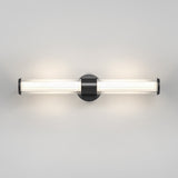 A modern wall-mounted light fixture with a cylindrical frosted glass tube and a black circular base, emitting a soft, diffused glow against a plain light gray wall.