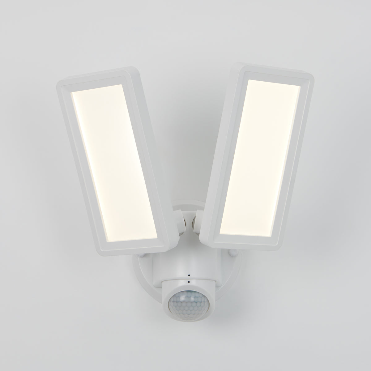 The Artika Sentinel outdoor Flat Panel Security light features two rectangular LED panels and a motion sensor below, all in a sleek white housing mounted on a white wall.