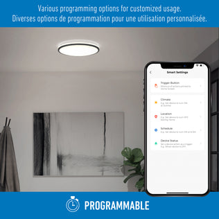A smartphone shows Macy 15 in. LED modern flush mount light by Artika, Alexa compatible, in a stylish room with art and a plant.