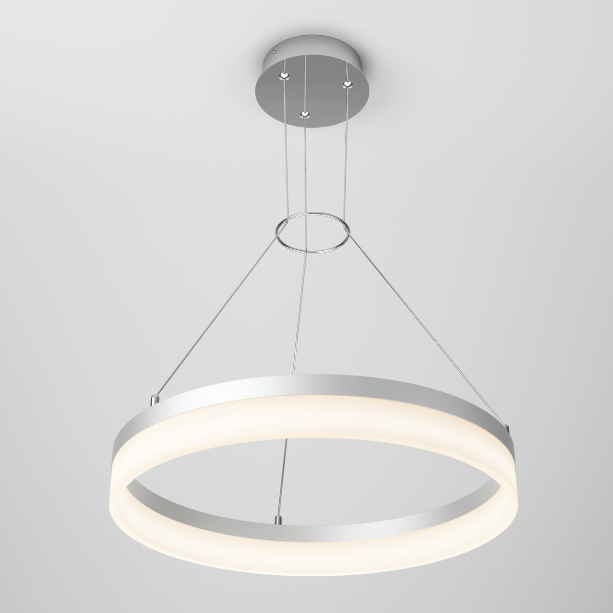 A modern circular LED pendant light with a silver frame, suspended from the ceiling by three thin cables, emits a soft white glow against a plain, light gray background.