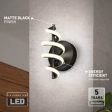 A modern wall sconce with a matte black finish and spiral LED light is mounted on a gray wall. Text highlights its energy efficiency, integrated LED, and 5-year warranty.