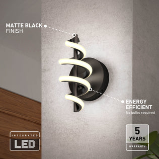 The Artika Chorus LED Wall Light, featuring a spiral LED design and matte black finish, is mounted on a gray wall. Labels highlight its energy efficiency, integrated LEDs, 5-year warranty, and no need for bulbs.