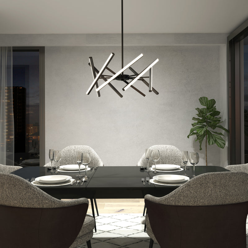 A modern dining room with a black table for four, gray upholstered chairs, an Artika Malibu LED pendant light, a potted plant in the corner, large windows, and a neutral color palette.