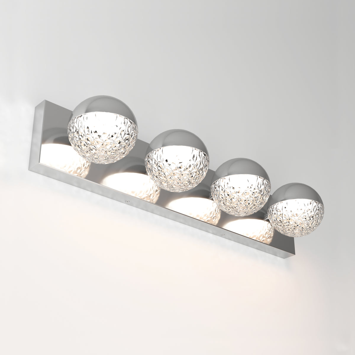 The Artika Carat 27-in (69 cm) Integrated LED Vanity Light Bar for Bathrooms features four textured spherical glass lamps on a sleek chrome rectangular base, creating a modern touch against a plain white wall.