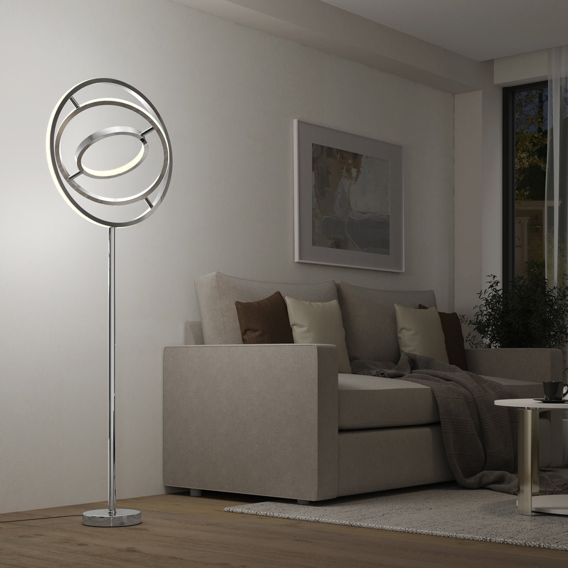A modern living room with a beige sofa, brown and cream cushions, a gray throw blanket, abstract wall art, and a unique circular LED floor lamp beside the sofa. A small round coffee table sits in front.