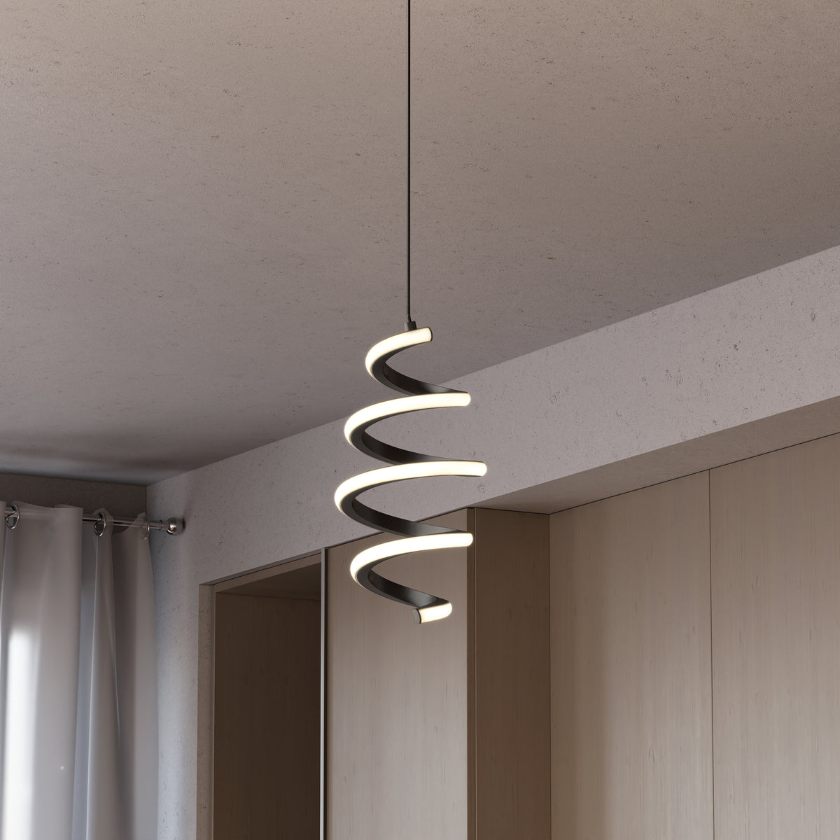 A modern spiral pendant light with integrated LED glows warmly, hanging from the ceiling in a minimalist room with light wood cabinets and white curtains.