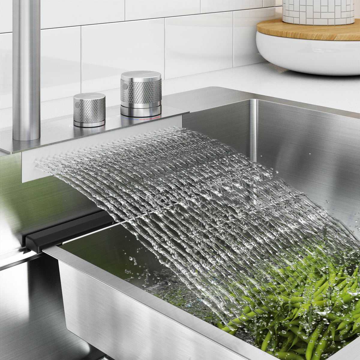 Water flows in a wide, flat stream from a modern kitchen faucet into a stainless steel sink, rinsing fresh green beans. The kitchen background is clean and contemporary.