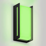 A modern wall sconce with a rectangular black frame and a frosted panel emits a bright green light, casting a soft glow on a plain light-colored wall.