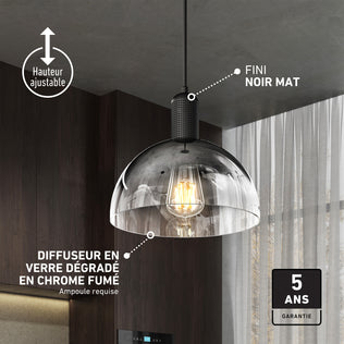 The Artika Nella Pendant without Bulbs hangs in a kitchen, featuring adjustable height, a matte black finish, and a smoked chrome glass shade. French text displays features with a 5-year warranty label in the bottom right corner.
