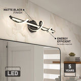 Modern matte black LED wall light with a twisted design is mounted above a bathroom mirror on a tiled wall. Text highlights its energy efficiency, integrated LED, and a 5-year warranty. A plant and towels are visible on a shelf below.