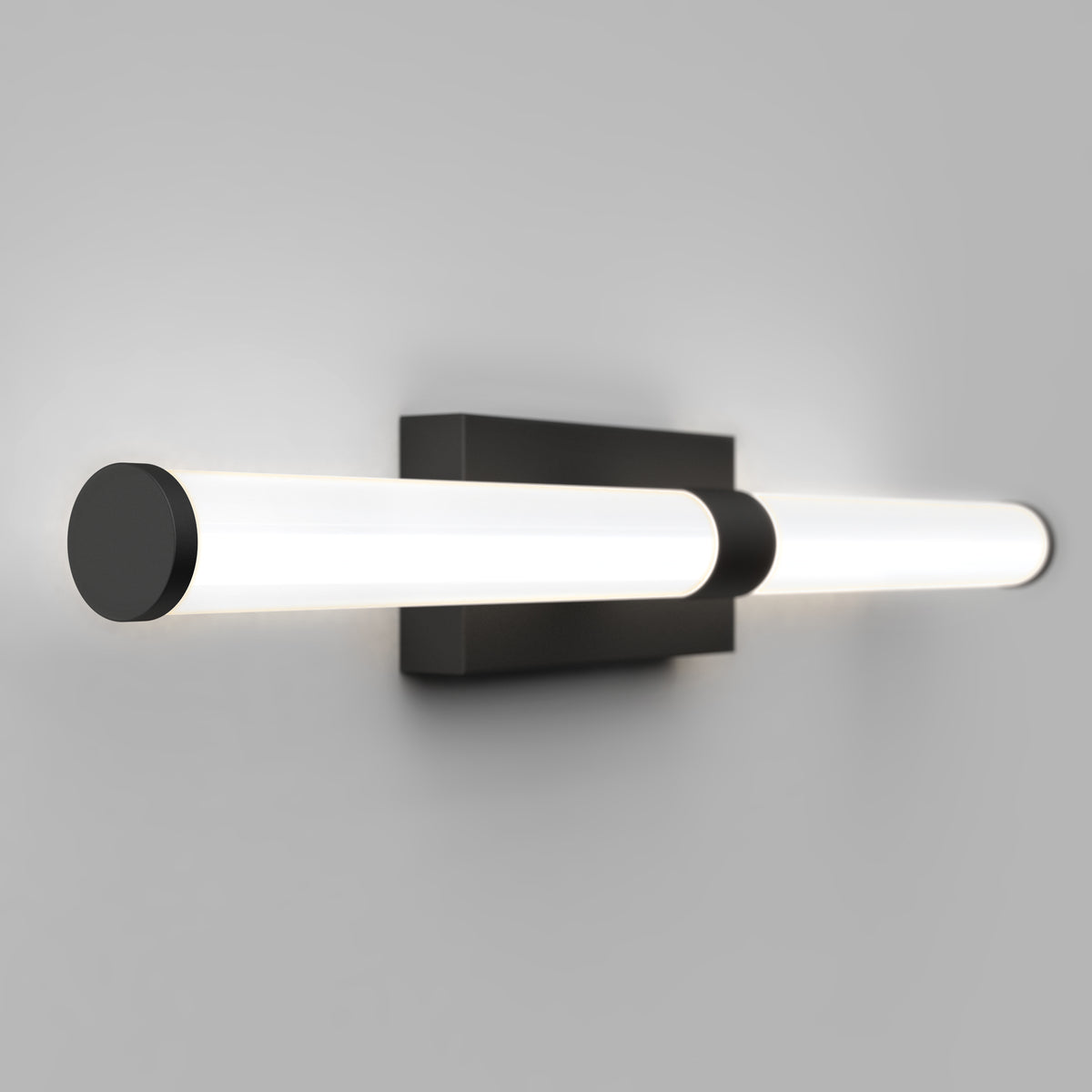 A modern wall-mounted light fixture with two parallel cylindrical LED lights and a rectangular black base, set against a plain gray background.