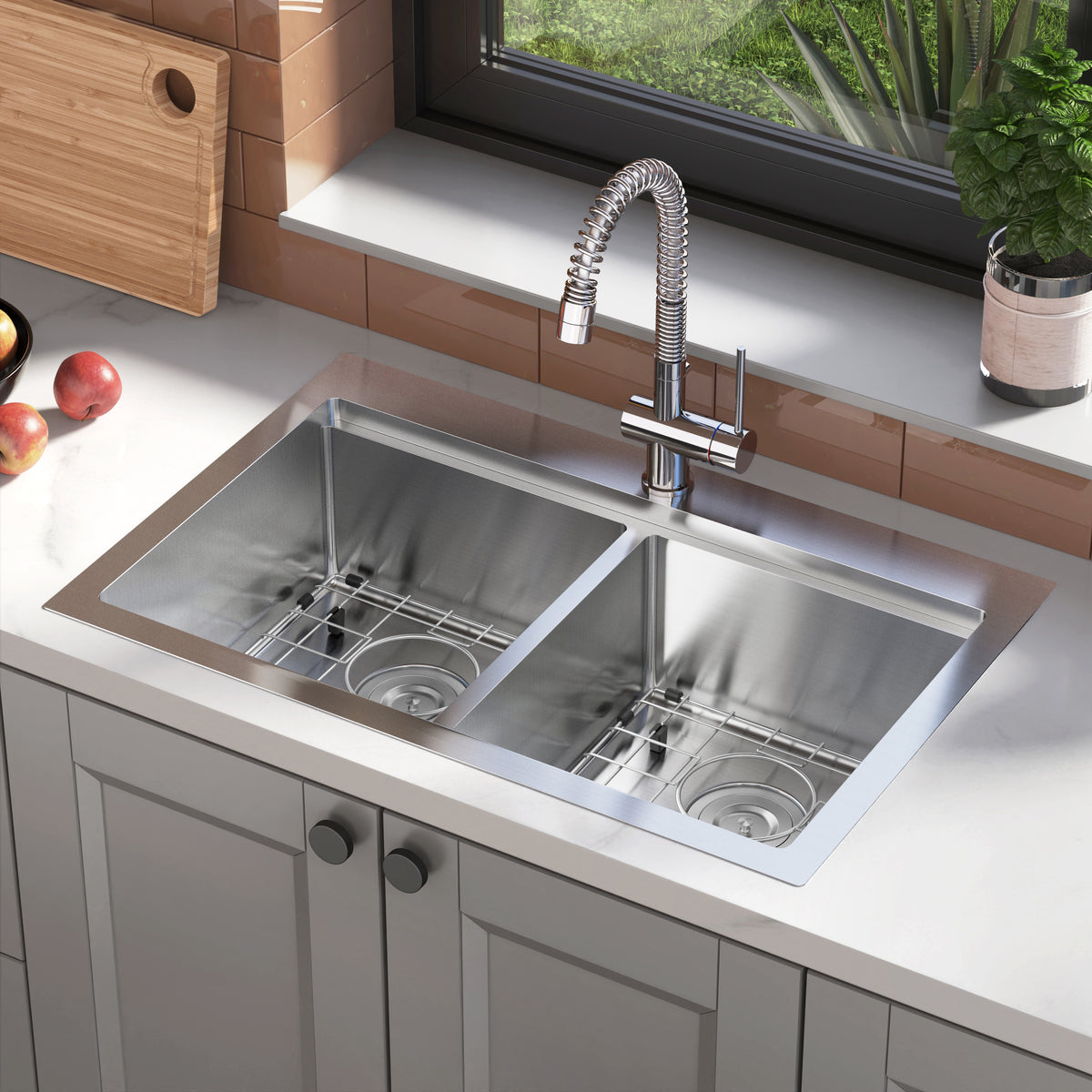 A modern stainless steel double kitchen sink with a flexible pull-down faucet, set in a white countertop. There are apples on the counter and a potted plant near the window above the sink.