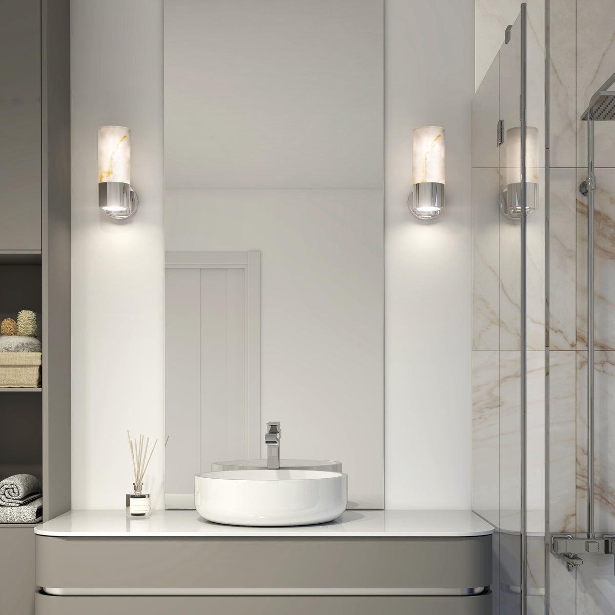 A modern bathroom showcases a round white vessel sink on a sleek vanity, flanked by two Artika Marble LED contemporary sconces. A glass shower and neatly folded towels complete the clean, minimalist space.