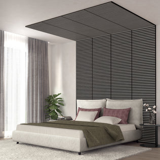 A modern bedroom featuring the Artika Sonolok 15.5 ft sound-absorbing wall panel kit (4-pack), a padded bed, mauve and white pillows, green throw blanket, sheer curtains, potted plant, and a small table with lamp and books.