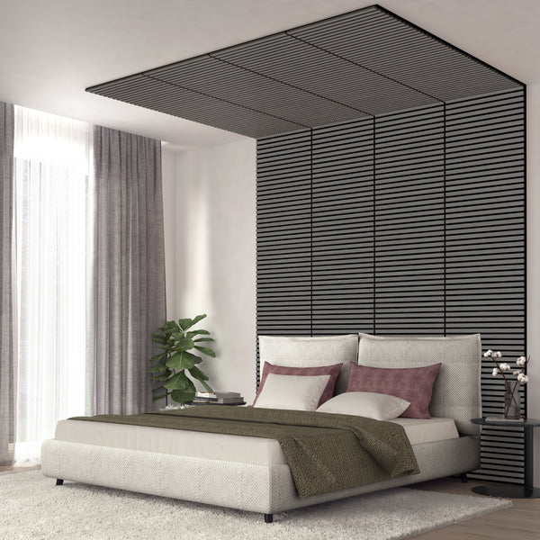 A modern bedroom featuring the Artika Sonolok 15.5 ft sound-absorbing wall panel kit (4-pack), a padded bed, mauve and white pillows, green throw blanket, sheer curtains, potted plant, and a small table with lamp and books.