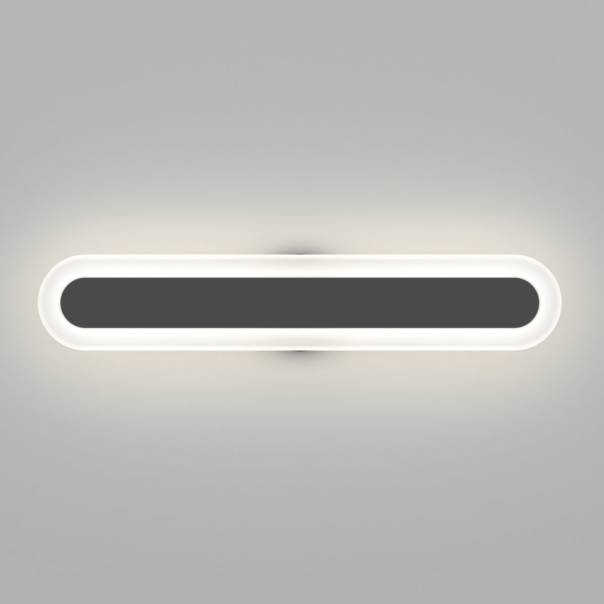 A modern, horizontal, oval-shaped wall light fixture emits a soft white glow against a plain gray wall. The center is dark, framed by a bright illuminated border.
