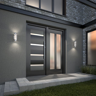 Modern front entrance with a sleek black double door featuring horizontal glass panels, flanked by two Artika Bubble Element LED indoor-outdoor lights, set in a gray stone and concrete exterior with a short walkway and green grass in front.