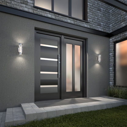 Modern front entrance with a sleek black double door featuring horizontal glass panels, flanked by two Artika Bubble Element LED indoor-outdoor lights, set in a gray stone and concrete exterior with a short walkway and green grass in front.