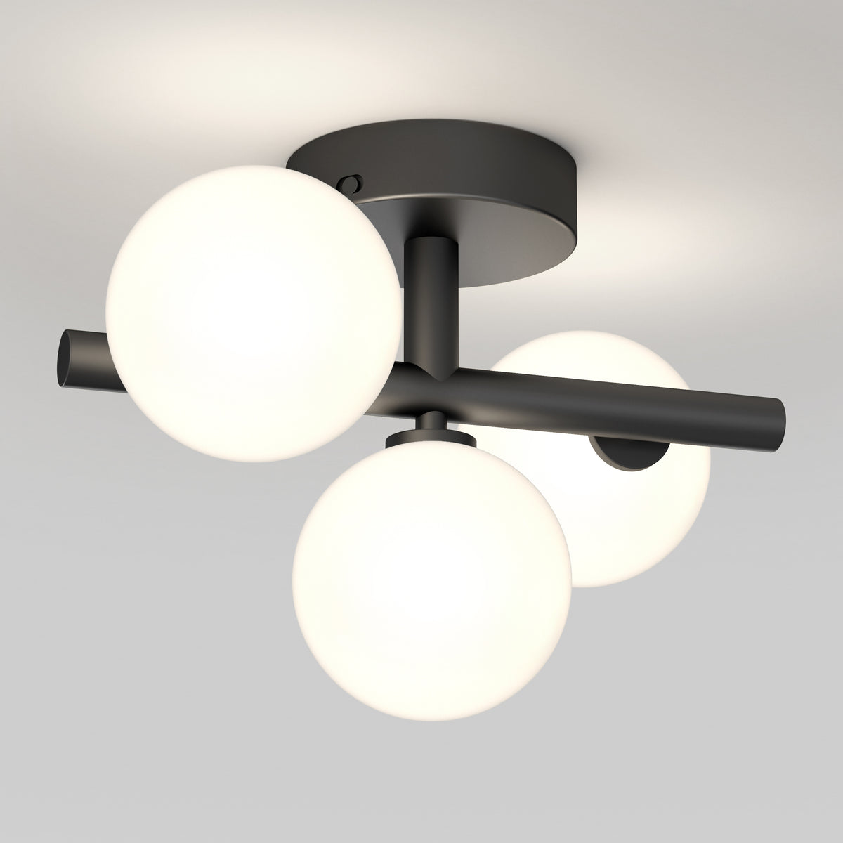 A modern ceiling light fixture with three glowing white glass globes attached to a matte black metal base and arms, mounted on a white ceiling.
