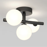 A modern ceiling light fixture with three glowing white glass globes attached to a matte black metal base and arms, mounted on a white ceiling.