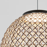 Close-up of a dome-shaped pendant light with a woven rattan or bamboo shade, featuring an intricate crisscross pattern, illuminated from within and hanging against a plain light gray background.