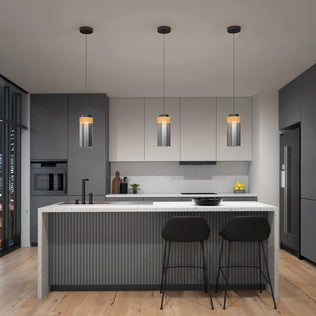 Modern kitchen with gray cabinets, white countertops, a central island with two black barstools, Artikas Hanson 1-light LED pendant 5 CCT above, wood flooring, built-in appliances, plus lemons and wooden utensils for decor.