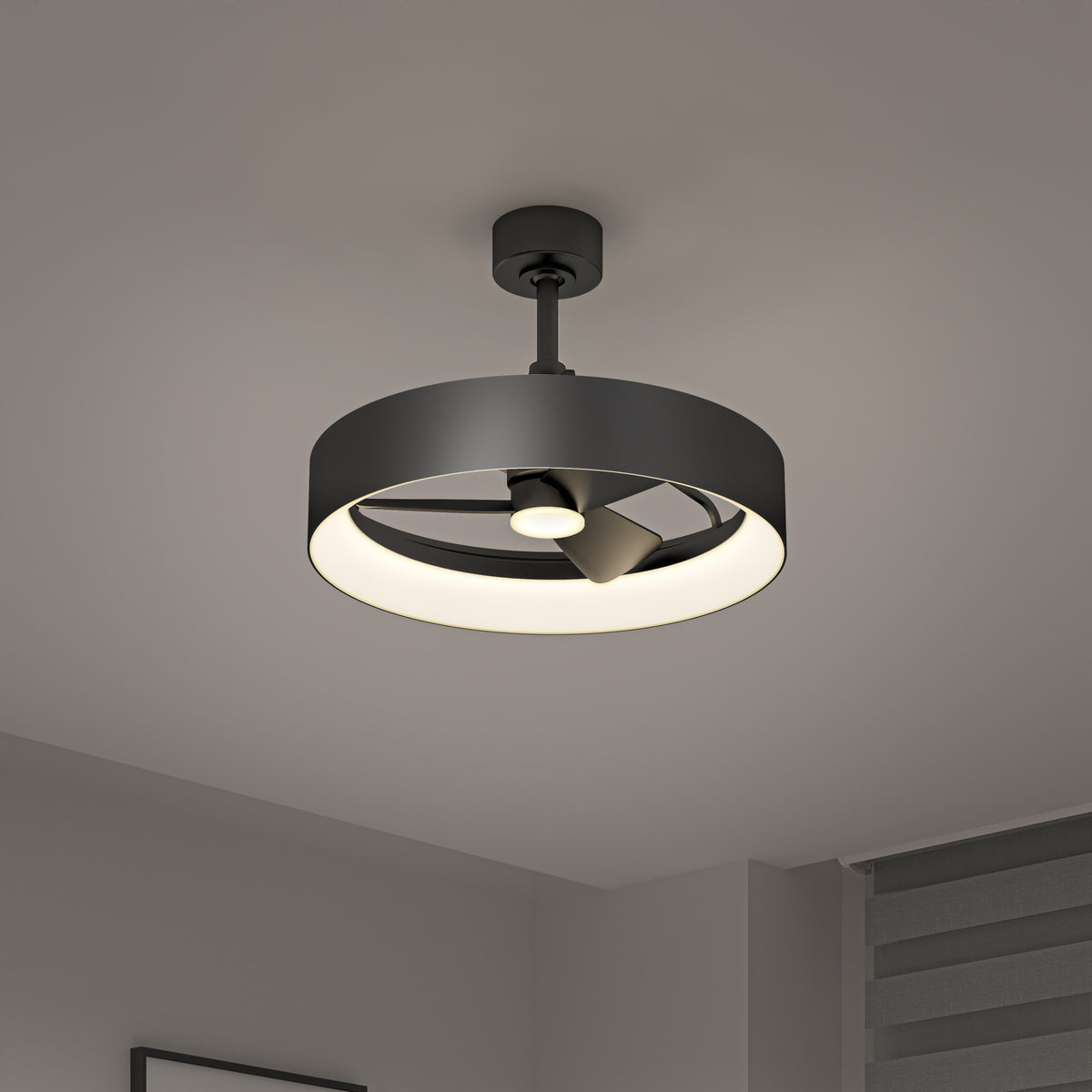 A modern black ceiling fan with an integrated circular LED light is mounted on a white ceiling in a minimalist room with gray walls and a window with horizontal blinds.