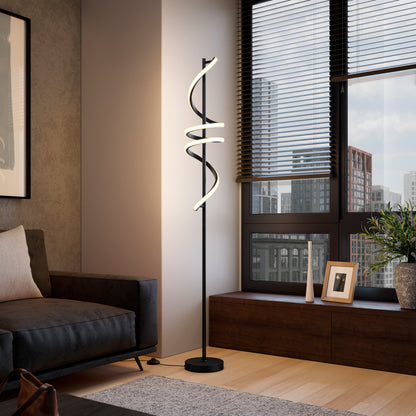 A modern living room features a dark sofa, the Artika Coda modern LED floor lamp 5CCT with white light, a low wooden cabinet with a plant and framed photo, and large windows showing city buildings outside.