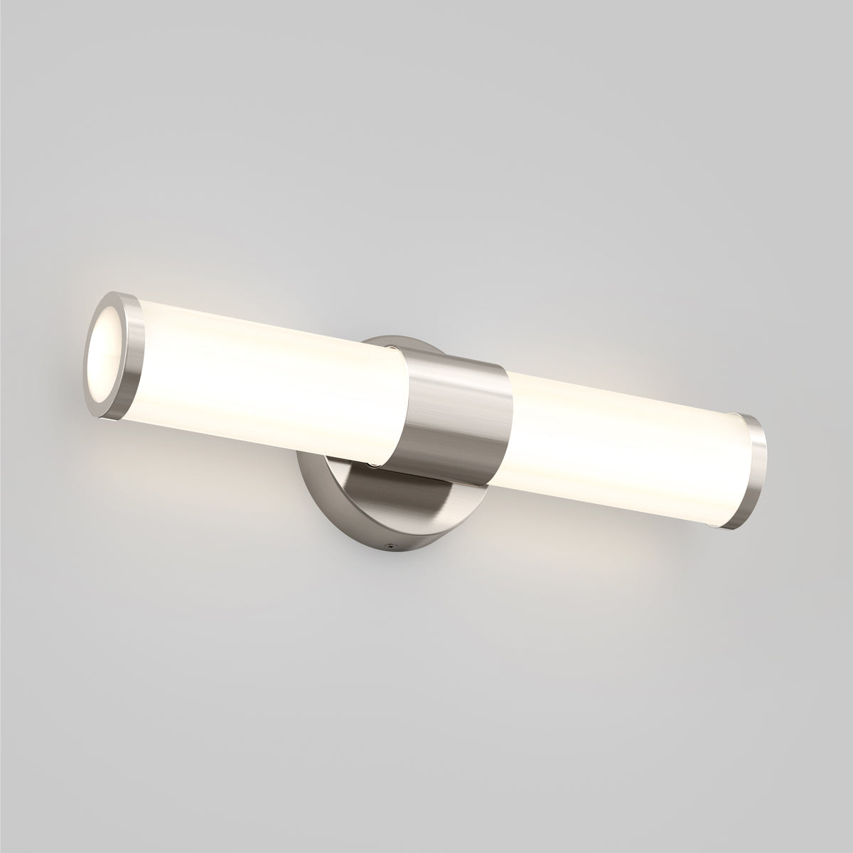 A modern wall-mounted LED light fixture with a cylindrical frosted glass shade and brushed metal accents, emitting soft white light against a plain light gray wall.