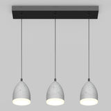 Three modern pendant lights with gray, dome-shaped shades hang in a row from a rectangular black ceiling mount against a plain light gray background. Each light is illuminated.