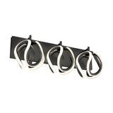 A modern wall-mounted light fixture with three abstract, looped LED light elements attached to a rectangular black base.