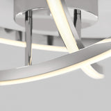 Close-up of a modern ceiling light fixture with curved, chrome arms and integrated LED strips emitting a soft white glow against a plain background.