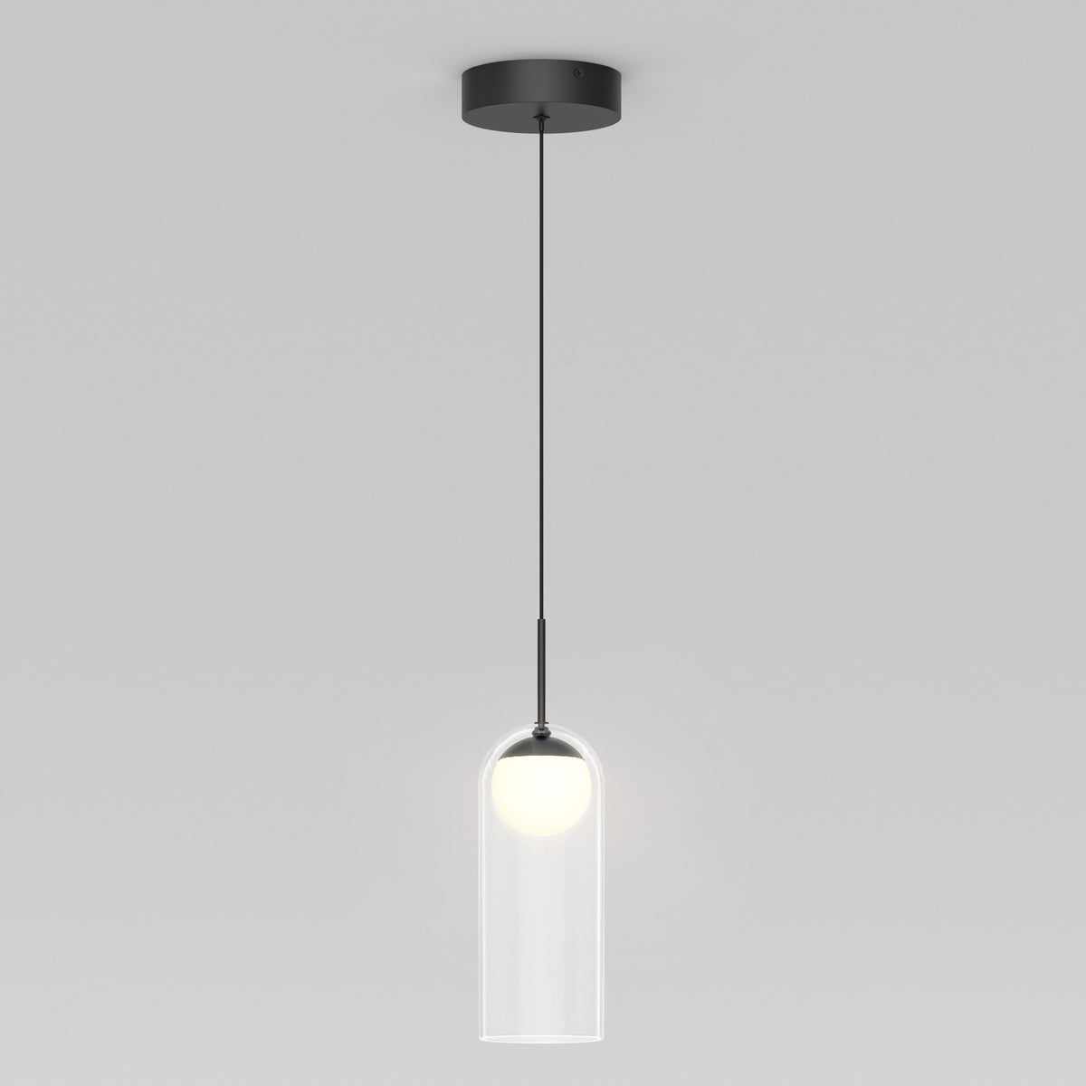 A modern pendant light with a black ceiling mount and cord, featuring a cylindrical clear glass shade and a glowing white bulb inside, hanging against a plain light gray background.
