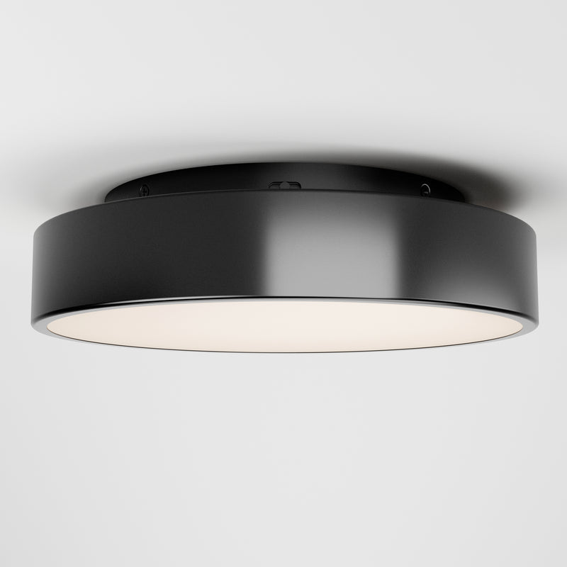The Artika Aiden LED flush mount is a modern, round black ceiling light with a smooth finish and white diffuser, shown installed on a plain white ceiling.