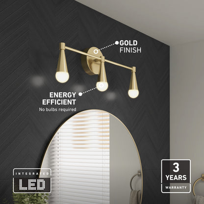 The Artika Wayden LED mid-century bathroom vanity light in a gold finish is mounted above a round mirror on a dark herringbone wall. Labels highlight Gold Finish, Energy Efficient, and 3 Years Warranty.