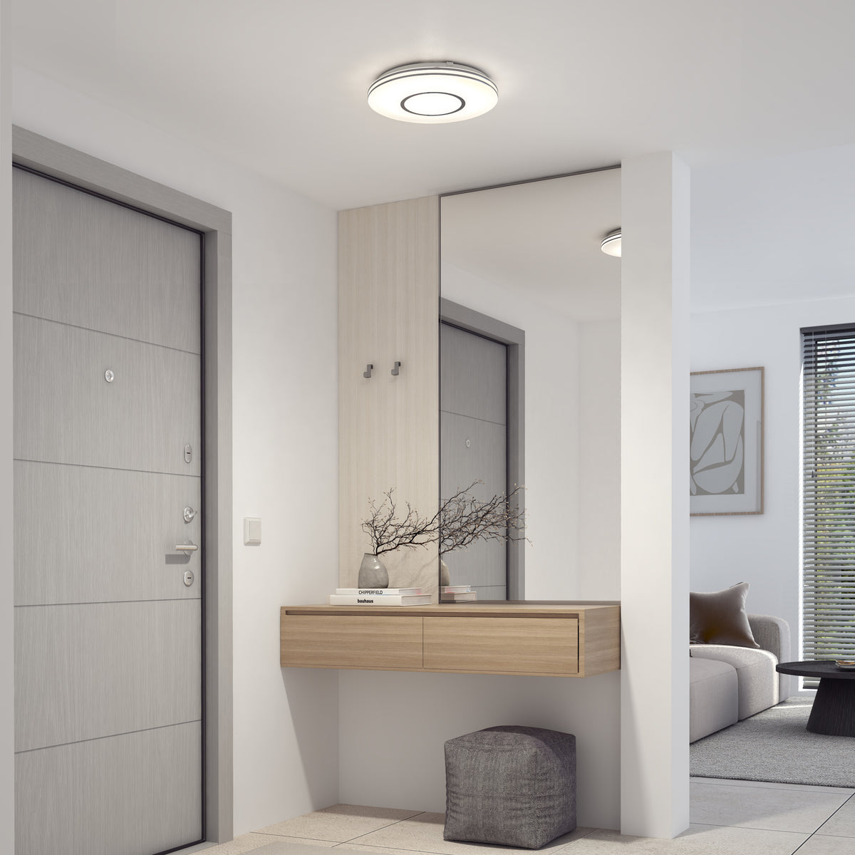 Modern entryway with wall mirror, console, decor, pouf, and Artika Horizon 13 in. LED flush mount light leading to bright living room.