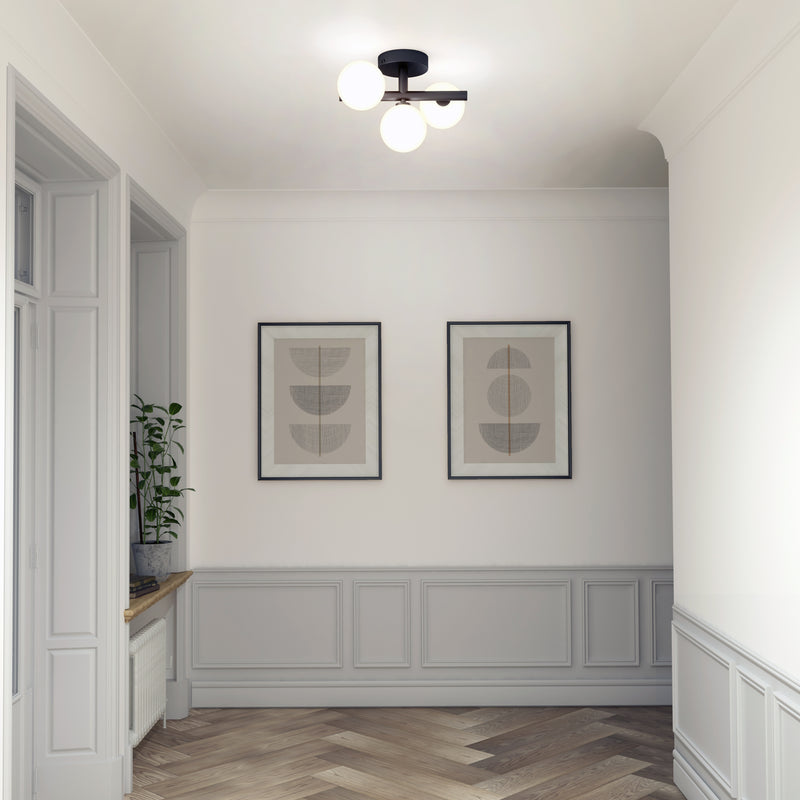 A minimal hallway with two framed abstracts, a potted plant, wood floors, and the Artika Bloom LED flush mount ceiling light.