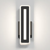 A modern, rectangular wall sconce with a black frame and a white illuminated border, mounted on a light gray wall. The light creates a soft glow on both sides of the fixture.