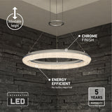 Modern circular LED pendant light with a chrome finish hangs from the ceiling in a room with dark stone walls. Text highlights its adjustable height, energy efficiency, 5-year warranty, and integrated LED.