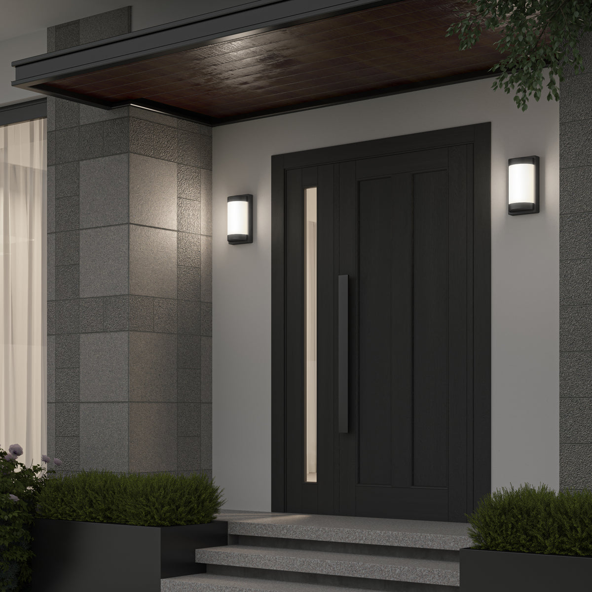 Modern front door entrance with dark wood door, vertical window panel, sleek handle, gray tiled walls, two lit wall sconces, and small shrubs on both sides of the steps.
