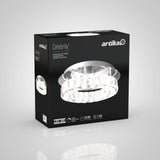 Black box packaging for an Artika Celebrity ceiling LED light fixture, featuring an image of the round, crystal-trimmed light. Text on the box highlights 50,000 hours lifespan and 1,450 lumens.